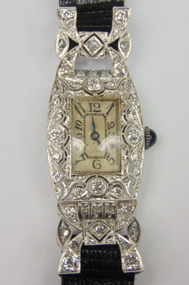 Montre du soir Art Décò en or blanc avec diamants taille brillant et rosaces, avec mouvement marqué "Longines" et saphir cabochon sur la couronne